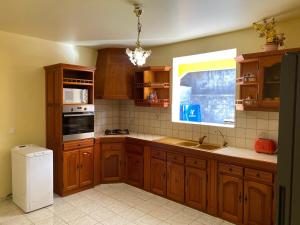 Una cocina con armarios de madera y un fregadero y una ventana. en Villa Bouillante, en Bouillante 16 fotos más