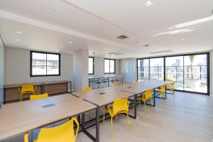 a large conference room with wooden tables and yellow chairs at Apto com piscina aquecida e rooftop in Curitiba +146 photos