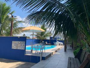 a swimming pool with a table and an umbrella at Pousada Jolie Maison in São Francisco do Sul