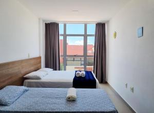 a hotel room with two beds and a large window at Areias do Mar ! 2 Quartos, VistaMar + Varanda A205 in Barra de São Miguel +21 photos