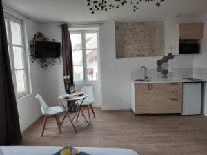 a kitchen with white walls and a table and chairs at Studio Kamelia in Saint-Aignan