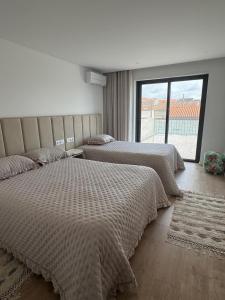 a bedroom with two beds and a large window at Aver Beach Haven in Póvoa de Varzim
