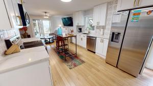 eine Küche mit weißen Schränken und einem Edelstahlkühlschrank in der Unterkunft Oceanfront Nest Down in Folly Beach