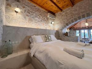 ein Schlafzimmer mit einem großen Bett und einer Steinwand in der Unterkunft Achelatis Traditional Guest Houses in Areopoli