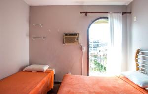 a room with two beds and an open window at Cobertura com piscina privativa próxima à praia in Cabo Frio