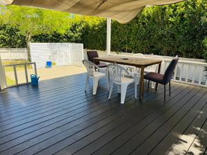 una terraza de madera con mesa, sillas y sombrilla en Seaside Luxury 4bedroom House, en Auckland