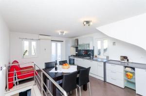 a kitchen with white cabinets and a table and chairs at Apartments Jasna in Baška Voda