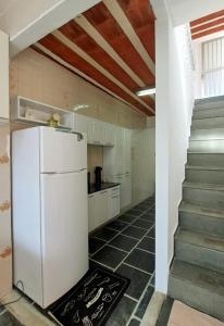 a white refrigerator in a kitchen with a staircase at Casa Costa Verde-Muriqui in Vila Muriqui