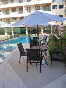 a table and chairs with an umbrella next to a pool at Apartamento Carnaval Cabo Frio in Cabo Frio