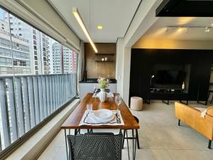 a living room with a table and a large window at Edição Jardim Paulista in Sao Paulo