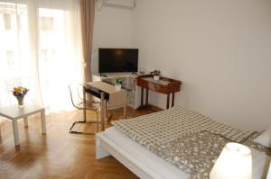 a bedroom with a bed, desk and television at Budapest Downtown Apartments in Budapest