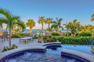 a swimming pool with chairs and palm trees and the ocean at Villa Las Brisas by Cabo Villas in San José del Cabo