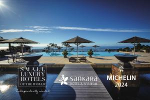 a resort with a pool with umbrellas and the ocean at Sankara Hotel & Spa Yakushima in Yakushima