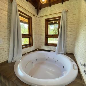 a large white tub in a room with two windows at Chale Villa do Valle in Monte Verde +95 photos