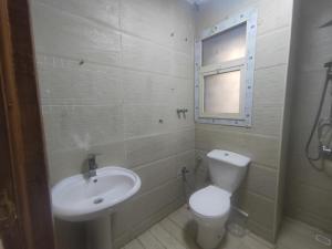 a bathroom with a white toilet and a sink at شقة فندقية قريبة من المتحف المصرى ومول مصر والاهرامات عجائب الدنيا السبعة in Cairo