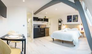 a bedroom with a bed and a table and a kitchen at Le petit joyau de Voltaire in Saint-Quentin