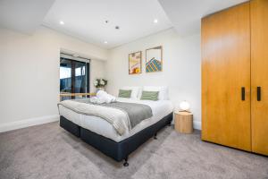 a bedroom with a bed and a wooden cabinet at Stunning Viaduct Apartment w Harbour views, Spa Pool and FREE Parking in Auckland +35 photos