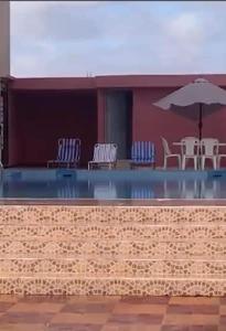a swimming pool with chairs and an umbrella at Charmante villa à Safi in Safi