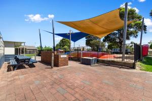 a picnic shelter with a bench and a fence at Waters Edge Holiday Park in Lakes Entrance