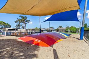 a colorful umbrella sitting on the sand in the sandbox at Waters Edge Holiday Park in Lakes Entrance