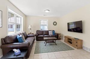a living room with a leather couch and a flat screen tv at Open Concept Lakefront Home with Rec Room and Fire Pit in Grand Junction +26 photos