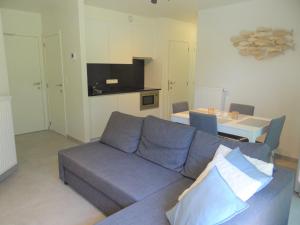 ニーウポールトにあるApartment Nieuwpoort near Beachの青いソファとテーブルのあるリビングルーム