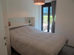 ニーウポールトにあるApartment Nieuwpoort near Beachのベッドルーム1室(ベッド1台付)、パティオへのドアが備わります。