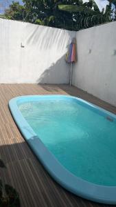 a blue swimming pool on a deck with an umbrella at Casa Salinopolis in Salinópolis +4 photos