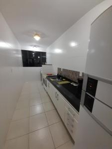 a kitchen with white cabinets and black counter tops at Apartamento Unamar Condomínio Verão Vermelho in Cabo Frio