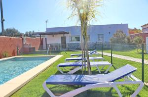 Una fila de tumbonas junto a una piscina. en Casa Nispero, en Conil de la Frontera