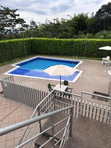 a pool with an umbrella and a table and chairs at Habitaciones privadas cerca al aeropuerto in Armenia