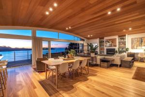 a dining room and living room with a view of the ocean at GARRATT VIEW - Coast & Country in Waiheke Island