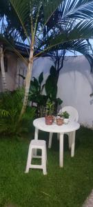 einem weißen Tisch mit Topfpflanzen und einem Stuhl in der Unterkunft Casa de veraneio in Caraguatatuba