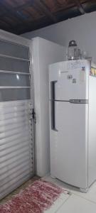 einen weißen Kühlschrank in einem Zimmer mit Tür in der Unterkunft Casa de veraneio in Caraguatatuba