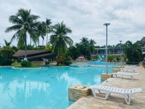 a large swimming pool with two white benches in a resort at Amontay Beach Resort in Nasipit