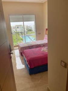 a bedroom with two beds and a large window at À LOUER APPARTEMENT à Casabay in Sidi Rahal