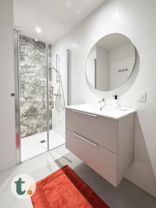un bagno bianco con lavandino e specchio di Tranquiloue - Appartement neuf proche PuyduFou ! a Les Herbiers