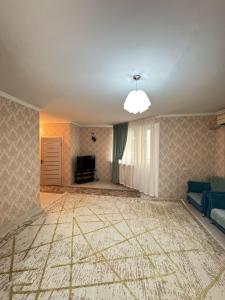 un soggiorno vuoto con divano blu e TV di Квартира посуточно жана кала a Tridtsatʼ Let Kazakhstana