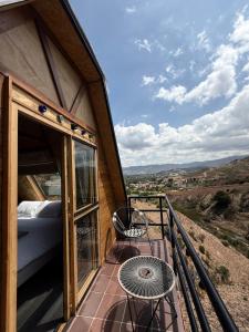 a room with a bed and a table on a balcony at Cabaña Mirador Serena en Villa de Leyva in Rodecia