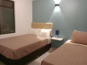 a bedroom with two beds and a light on the wall at Envigado tradicion y modernidad in Envigado