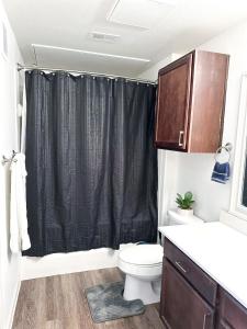 a bathroom with a toilet and a black shower curtain at The Frisco Upscale in Frisco
