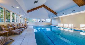 a pool in a room with chairs and a swimming pool at The Sebel Bowral Heritage Park in Bowral