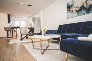 a living room with a blue couch and a table at Exklusives Apartment Sinsheim Luxus, 75 TV & Top Lage WeHome Premium in Sinsheim