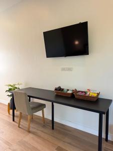 a black table with a chair and a television on a wall at แคมป์คาฟ จันทบุรี ( Kamp Kaff) in Ban Khlong Som (1)