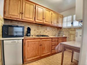 une cuisine avec des armoires en bois et un réfrigérateur blanc dans l'établissement Appartement 6 pers, jardinet privatif, WiFi - FR-1-475-145, à Saintes-Maries-de-la-Mer