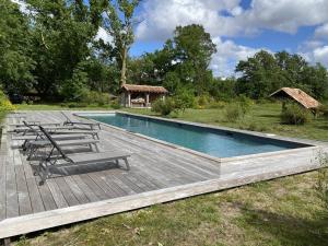 einen Pool mit Stühlen und eine Holzterrasse in der Unterkunft Domaine de Coursat avec piscine chauffée et services haut de gamme pour 16 personnes - FR-1-791-35 in Castets