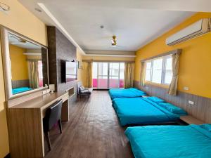 a room with three beds and a desk and a tv at I WoW in Xiaoliuqiu