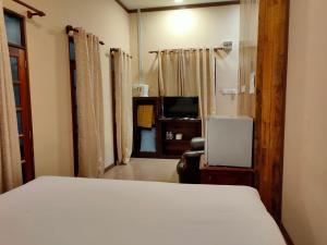 a bedroom with a white bed and a television at Kembara Resort, Merang in Setiu