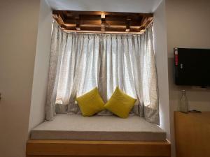 a window seat with two yellow pillows in a room at Maple house ladakh in Leh
