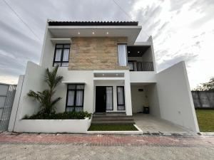 a white house with a palm tree in front of it at Aruna Kalasan in Kalasan